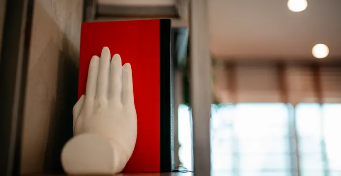 Escultura de mão sobre livro vermelho no consultório do Dr. Jean Almeida, Av. Paulista